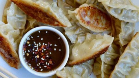 Pork Potstickers with Citrus-Soy Dipping Sauce on white plate with chopsticks