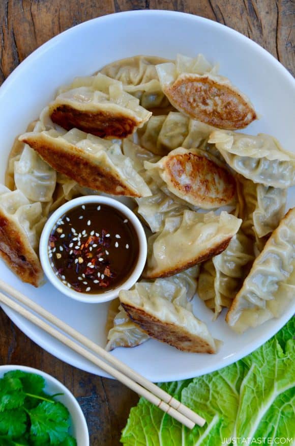 Pork Potstickers with Citrus-Soy Dipping Sauce on white plate with chopsticks