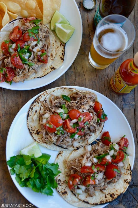 Top down view of Instant Pot Carnitas topped with cherry tomato pico de gallo salsa on white plate with tortilla chips