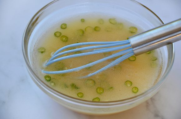 Glass bowl containing whisk and lime dressing 