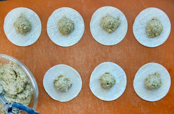 Gyoza wrappers with pork potstickers filling on wood cutting board 