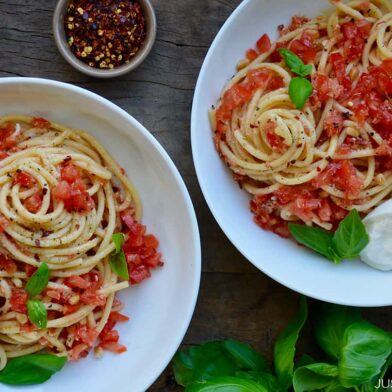 White bowls containing pasta with no-cook tomato sauce, fresh basil and burrata garnished with red pepper flakes