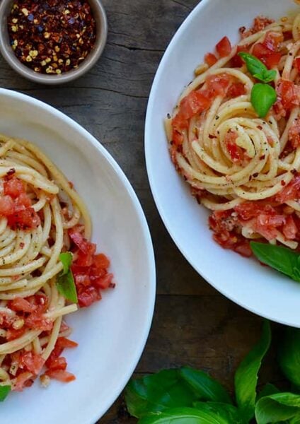 White bowls containing pasta with no-cook tomato sauce, fresh basil and burrata garnished with red pepper flakes