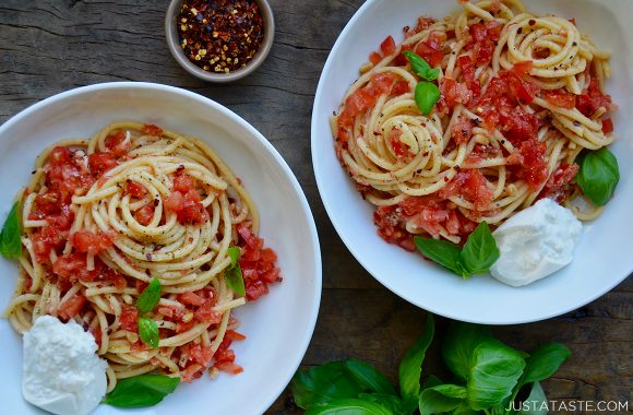 White bowls containing pasta with no-cook tomato sauce, fresh basil and burrata garnished with red pepper flakes
