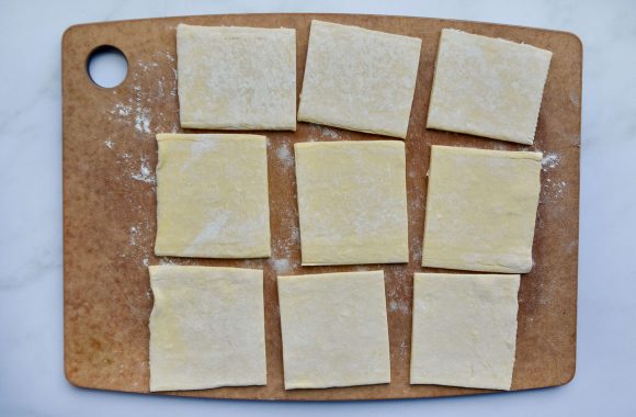 Cutting board containing nine puff pastry squares