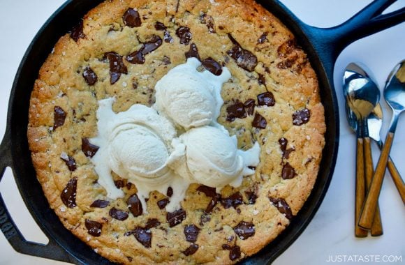 Homemade Skillet Chocolate Chip Cookie topped with three scoops of vanilla ice cream next to spoons