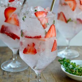 A clear glass containing sliced strawberries and crushed ice