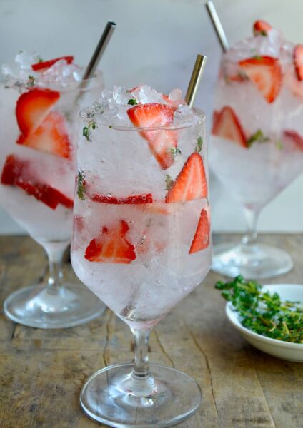 A clear glass containing sliced strawberries and crushed ice