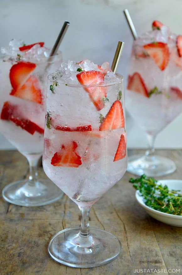 A clear glass containing sliced strawberries and crushed ice for a Sparkling Strawberry Cocktail