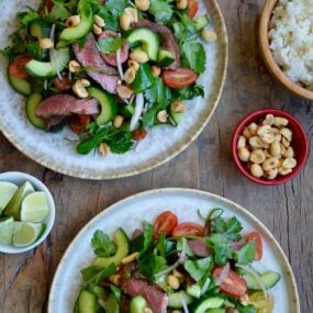 Two plates containing easy Thai Beef Salad with Lime Dressing garnished with peanuts