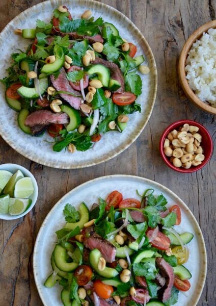 Two plates containing easy Thai Beef Salad with Lime Dressing garnished with peanuts