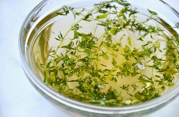 A clear glass bowl containing thyme syrup