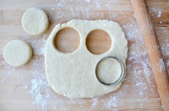 Rolling pin next to biscuit dough with circular cookie cutter 