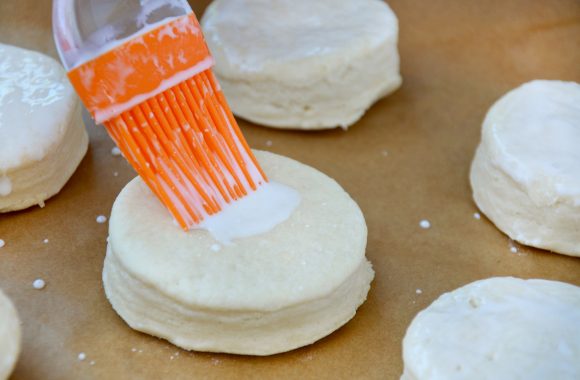 Brushing the top of a biscuit with buttermilk