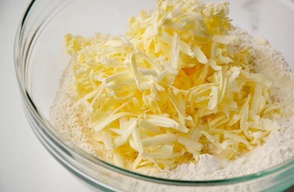 Glass bowl containing all-purpose flour and grated butter