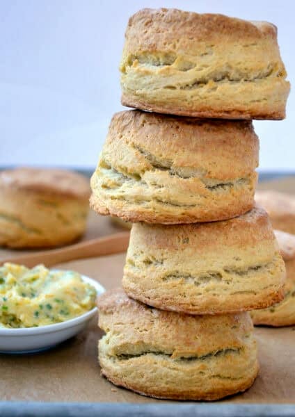 A tall stack of homemade buttermilk biscuits with a small bowl containing homemade honey butter nearby.