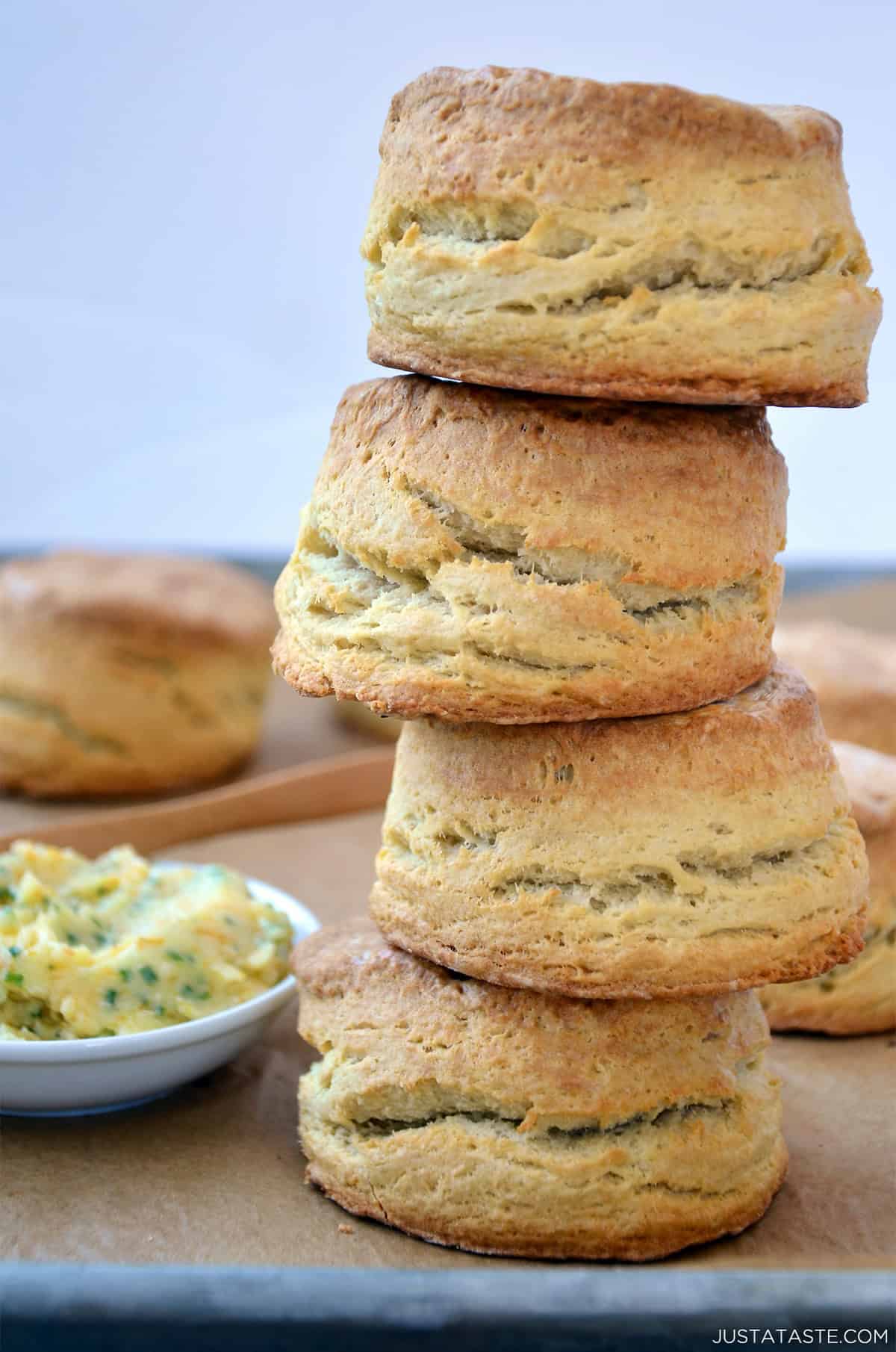 A tall stack of homemade buttermilk biscuits with a small bowl containing homemade honey butter nearby.