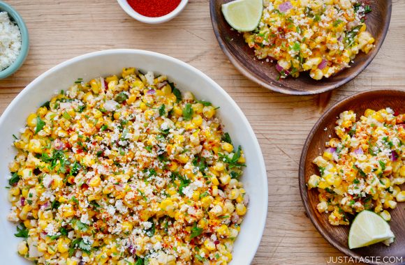 Easy Elote Corn Salad with lime wedges and crumbled Cotija cheese