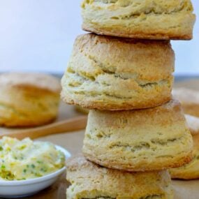 Easy Homemade Buttermilk Biscuits stacked four high next to dish with honey butter