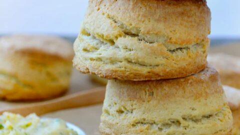 Easy Homemade Buttermilk Biscuits stacked four high next to dish with honey butter