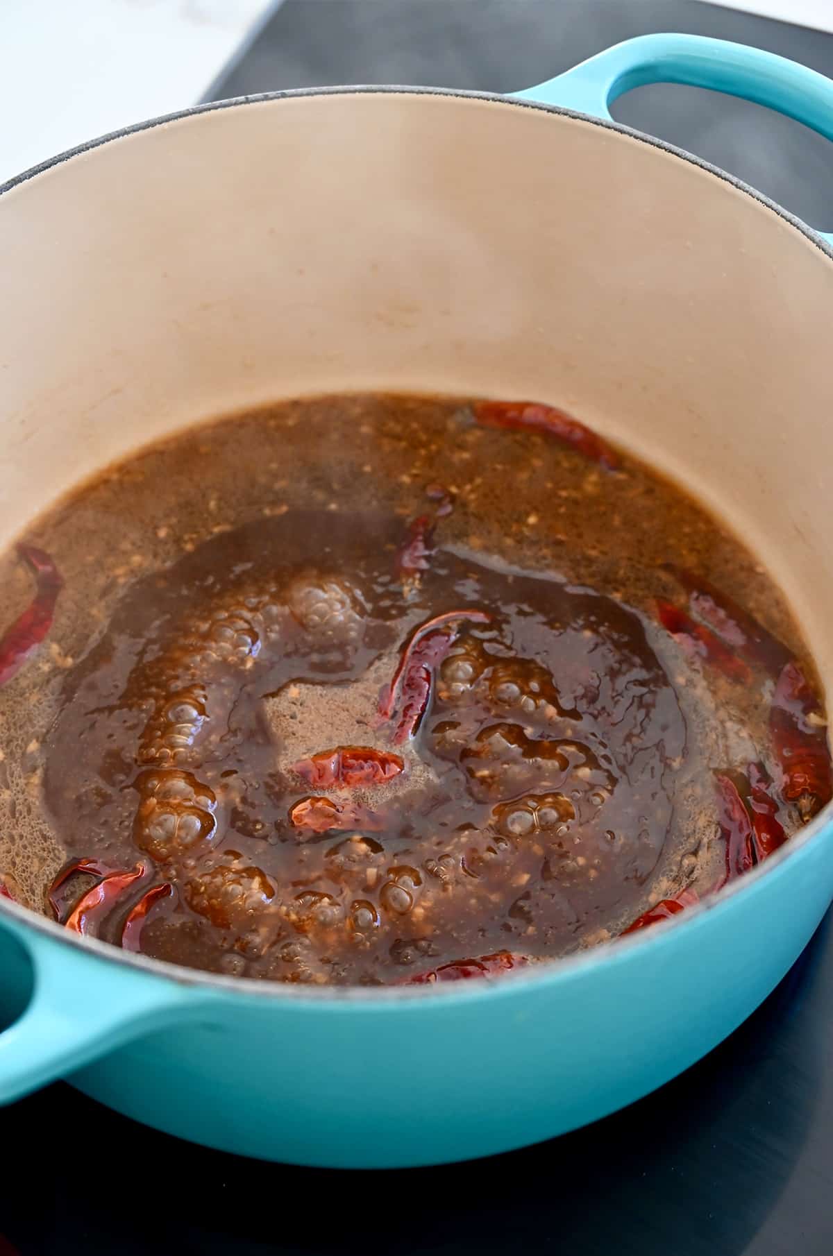 General Tso's sauce in a large blue Dutch oven on a stovetop.