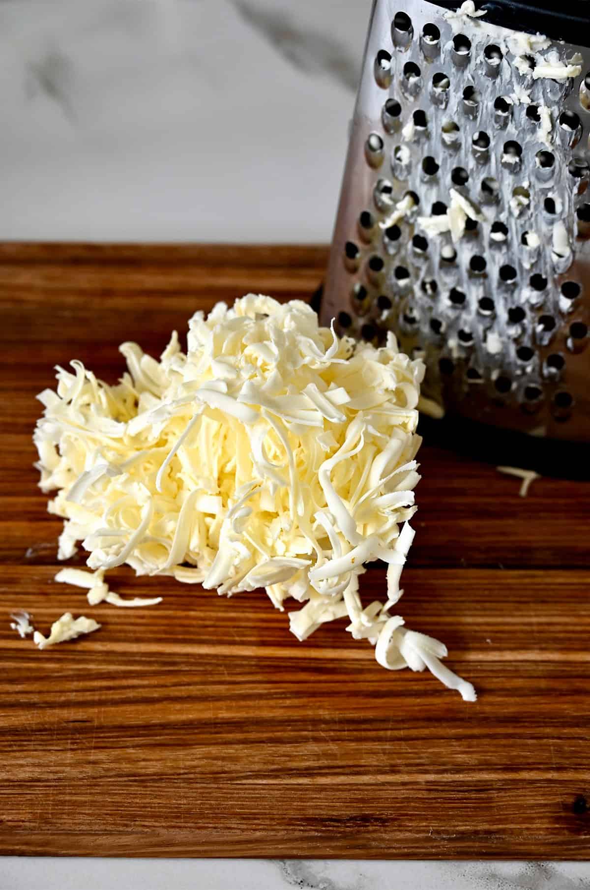 Grated butter on a cutting board next to a box grater.