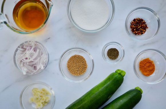 Glass bowls filled with ingredients to make zucchini pickles