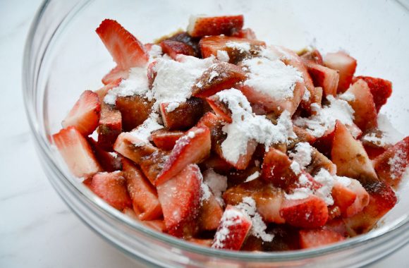 Glass bowl containing fresh strawberries and sugar