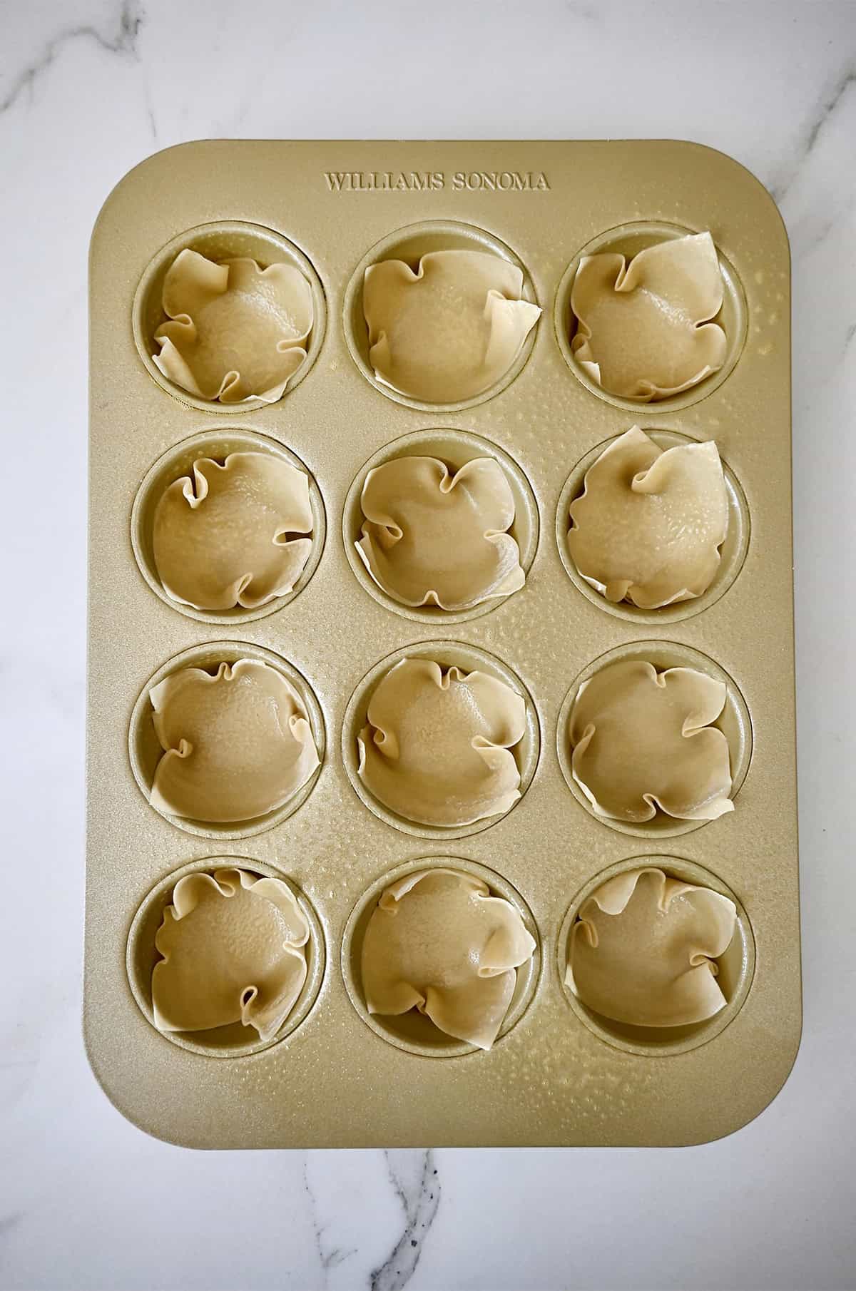 Wonton wrappers in a standard 12-cup muffin pan.