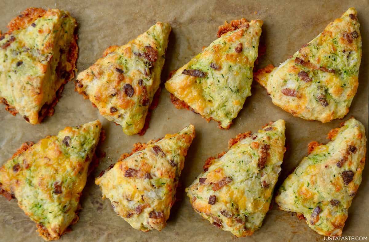 Freshly baked bacon cheddar zucchini scones on a parchment paper-lined baking sheet.