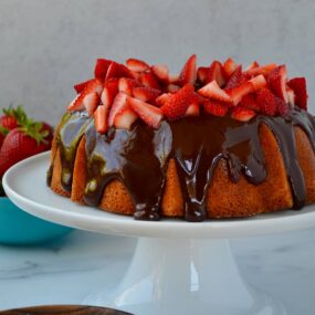 A cake with chocolate frosting and strawberries on a white cake stand