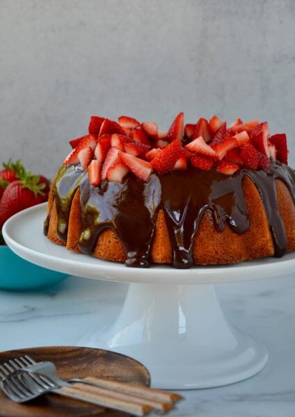 A cake with chocolate frosting and strawberries on a white cake stand