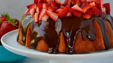 A cake with chocolate frosting and strawberries on a white cake stand