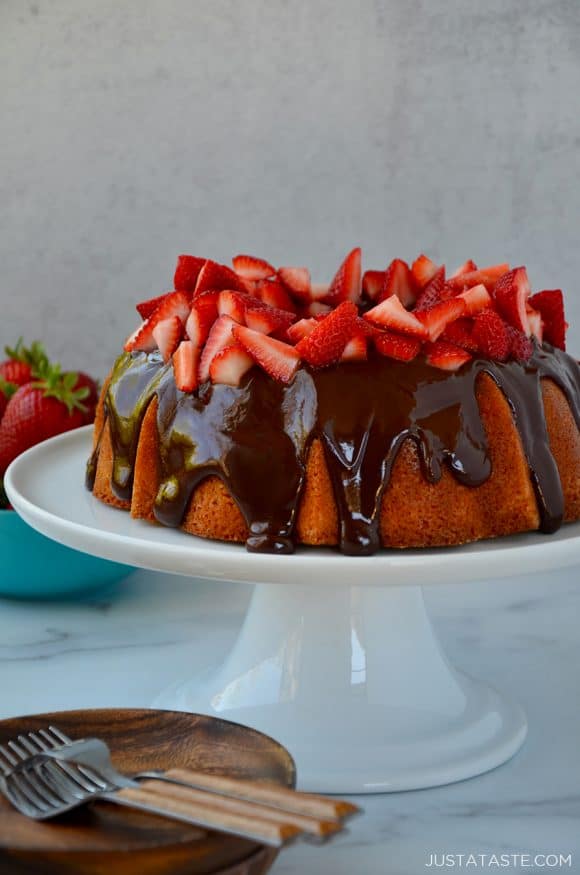 A cake with chocolate frosting and strawberries on a white cake stand