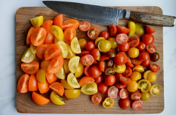 Chopped heirloom cherry tomatoes on wood cutting board with knife