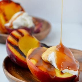 Grilled peach sundaes dripping with boozy caramel sauce and topped with vanilla ice cream