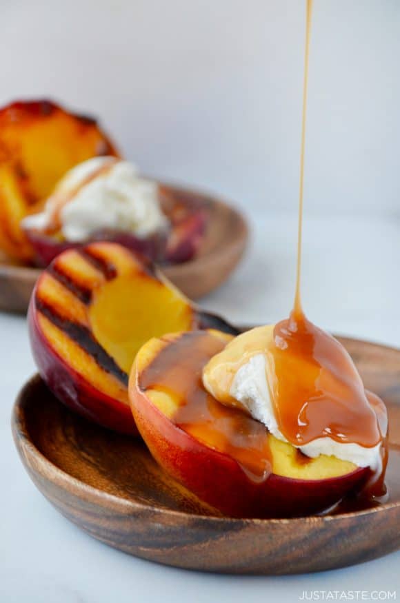Grilled peach sundaes dripping with boozy caramel sauce and topped with vanilla ice cream