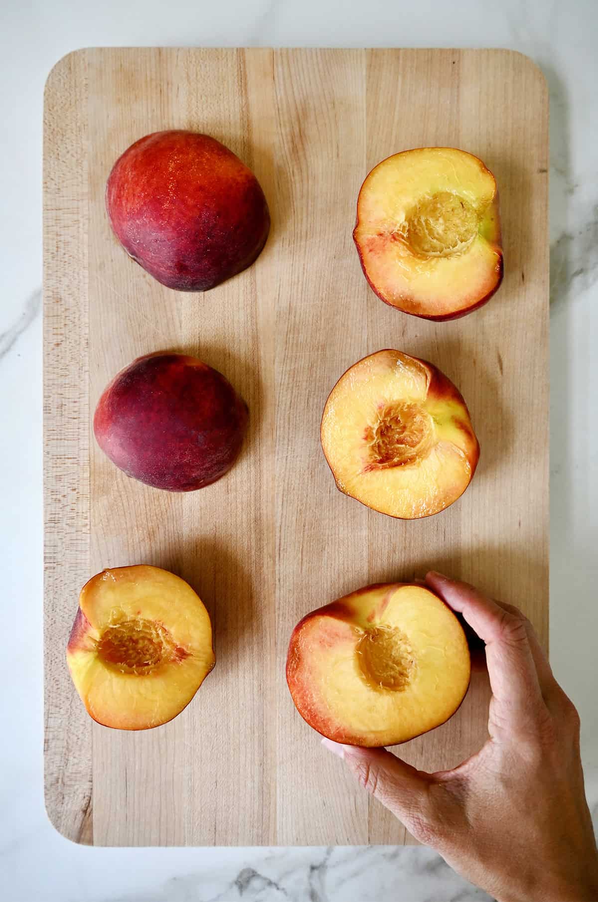 Halved peaches with the pits removed on a cutting board.