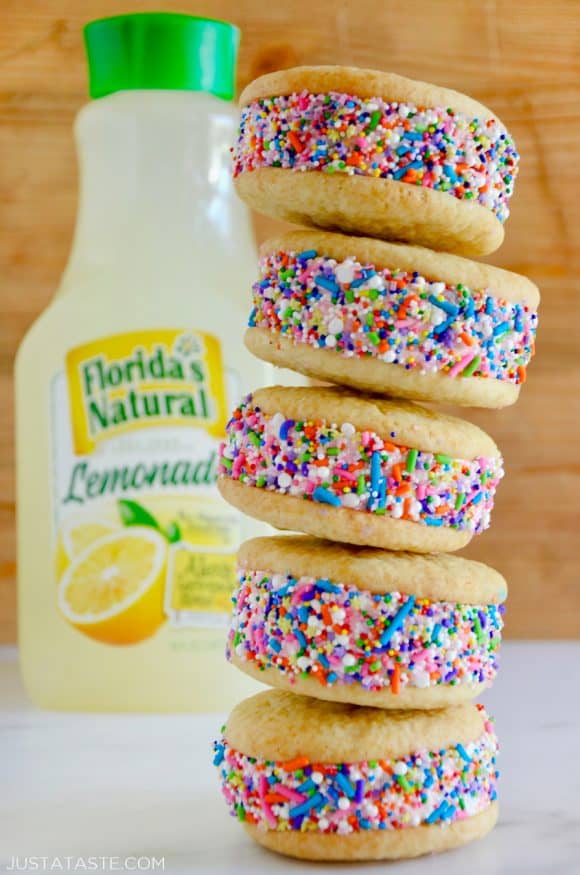 A stack of lemon ice cream sandwiches coated in sprinkles with a bottle of lemonade behind them