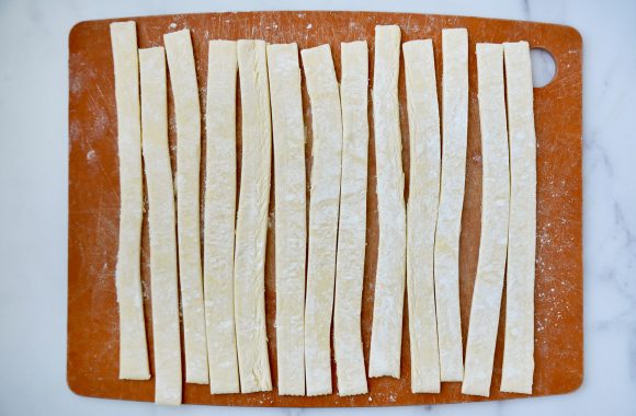 Strips of puff pastry on wood cutting board