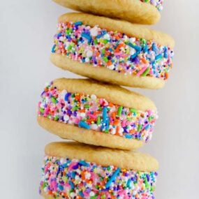 A close-up shot of a stack of ice cream cookie sandwiches rolled in rainbow sprinkles