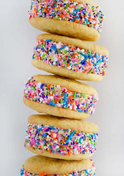 A close-up shot of a stack of ice cream cookie sandwiches rolled in rainbow sprinkles