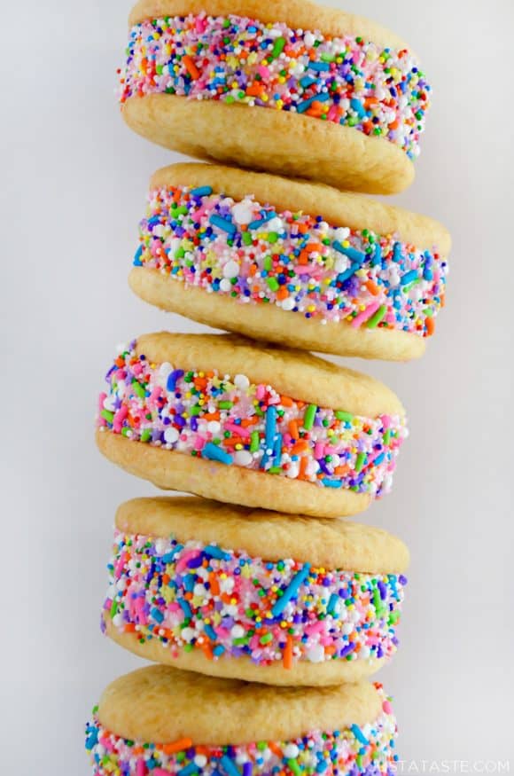 A close-up shot of a stack of ice cream cookie sandwiches rolled in rainbow sprinkles