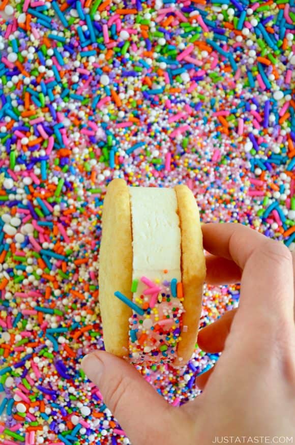 A close-up shot of a cookie ice cream sandwich being rolled in sprinkles