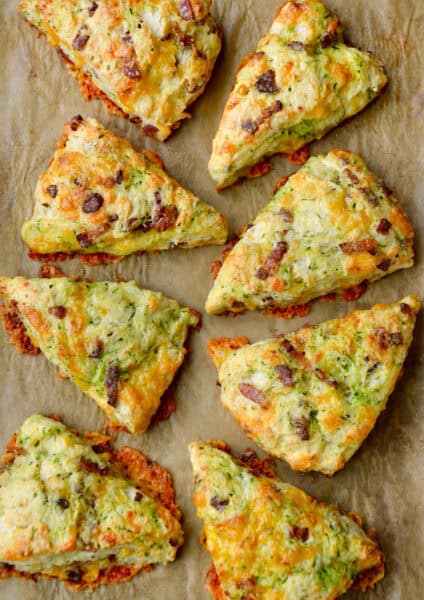 Eight savory Zucchini Bacon Cheddar Scones on brown parchment paper.