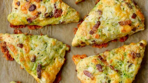Eight savory Zucchini Bacon Cheddar Scones on brown parchment paper.