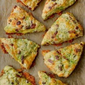 Top down view of eight savory Zucchini Bacon Cheddar Scones on brown parchment paper
