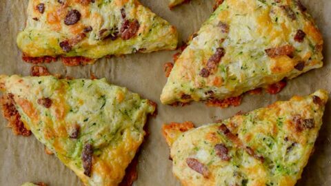 Top down view of eight savory Zucchini Bacon Cheddar Scones on brown parchment paper