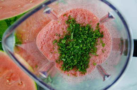 Blender containing puréed watermelon and finely chopped mint 