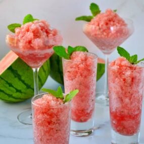 Various sized cocktail glasses filled with Boozy Watermelon Granita and fresh mint